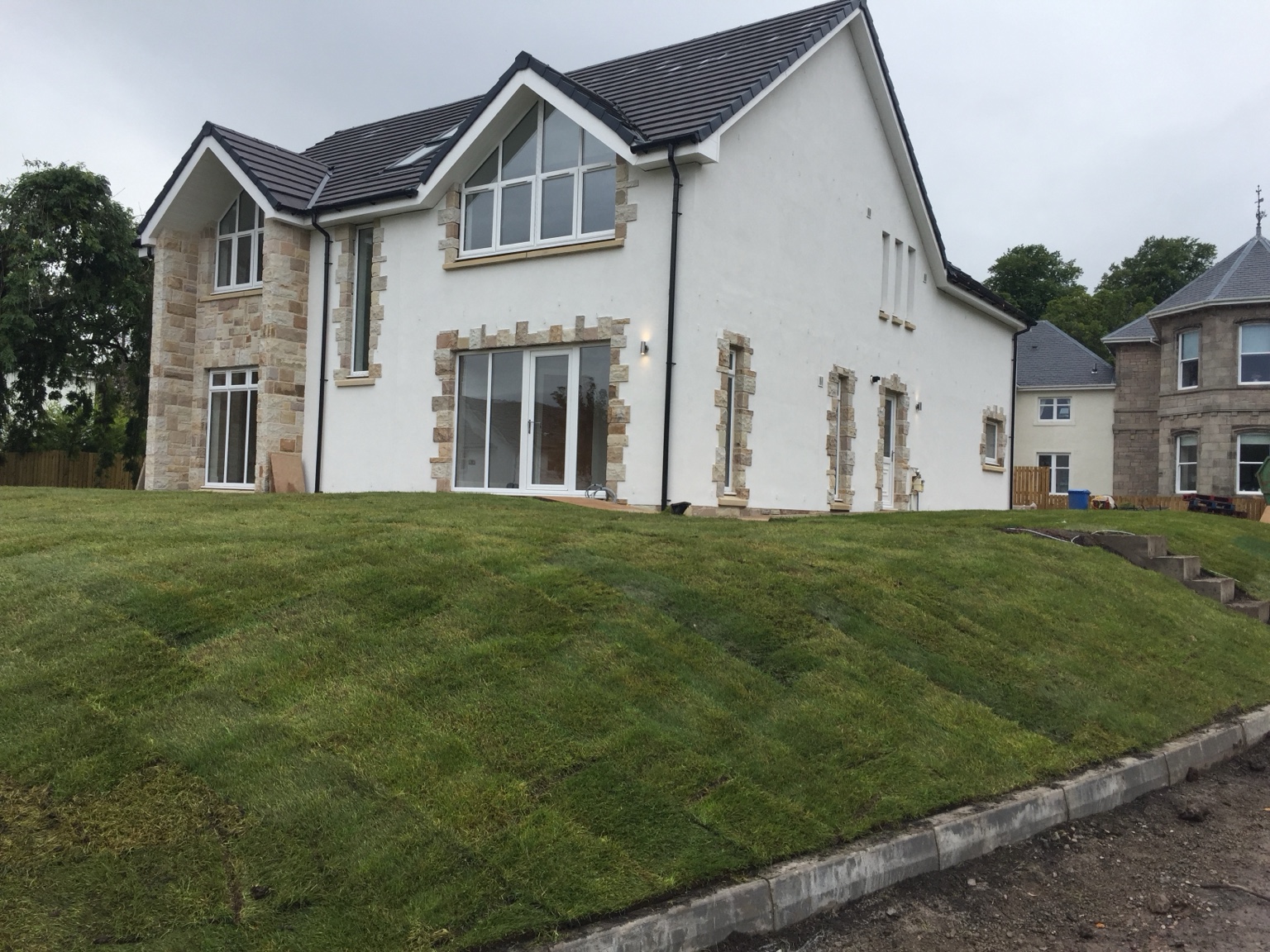 Completed side and rear elevation with rendered walls and natural-stone detailing